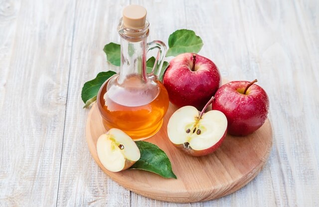 사과식초가 테이블에 사과와 함께 있다.